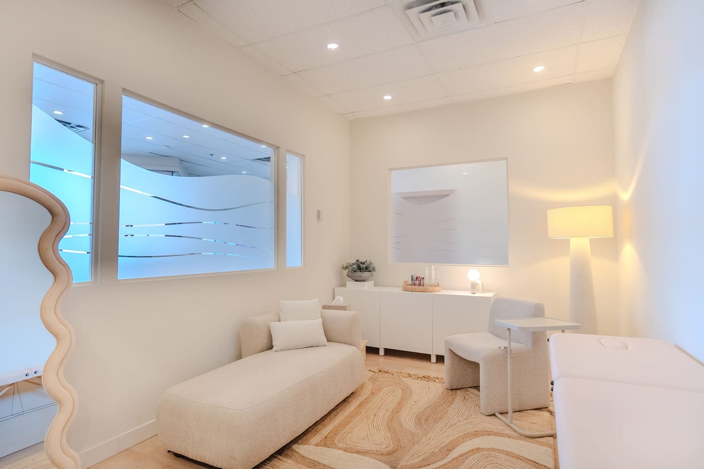 A calm treatment and lactation room with a chaise, soft lighting, and a frosted wave window