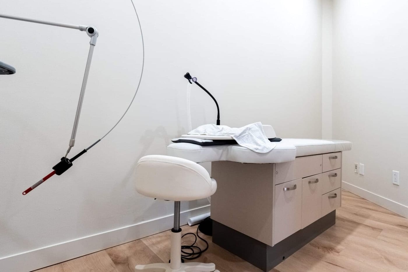 A treatment room with an exam table, clinician stool, and adjustable light
