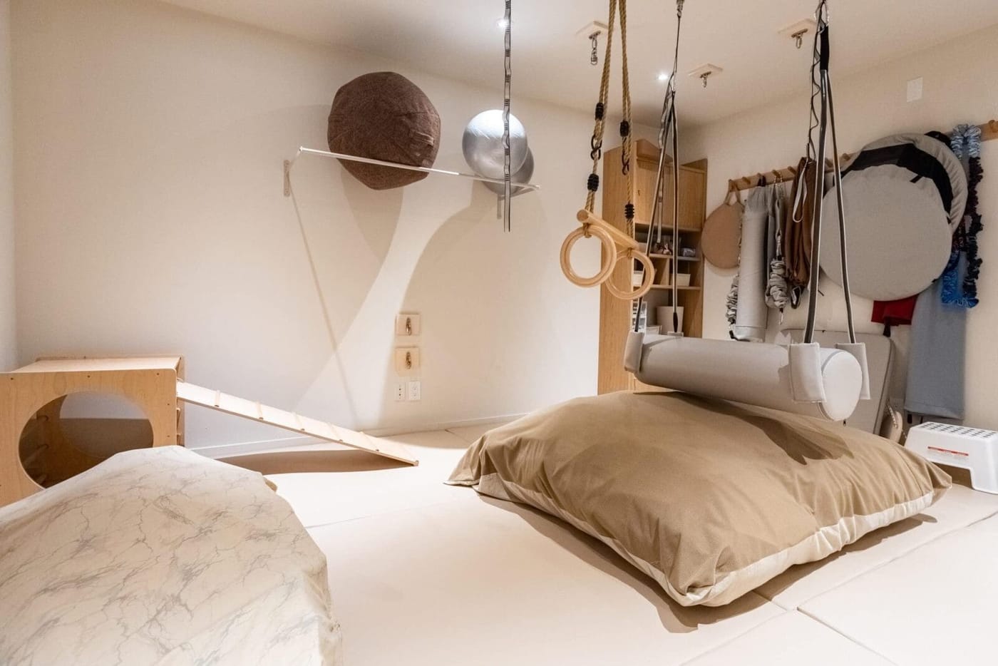 The sensory gym, with suspended swings, gymnastic rings, a climbing ramp, and crash pads